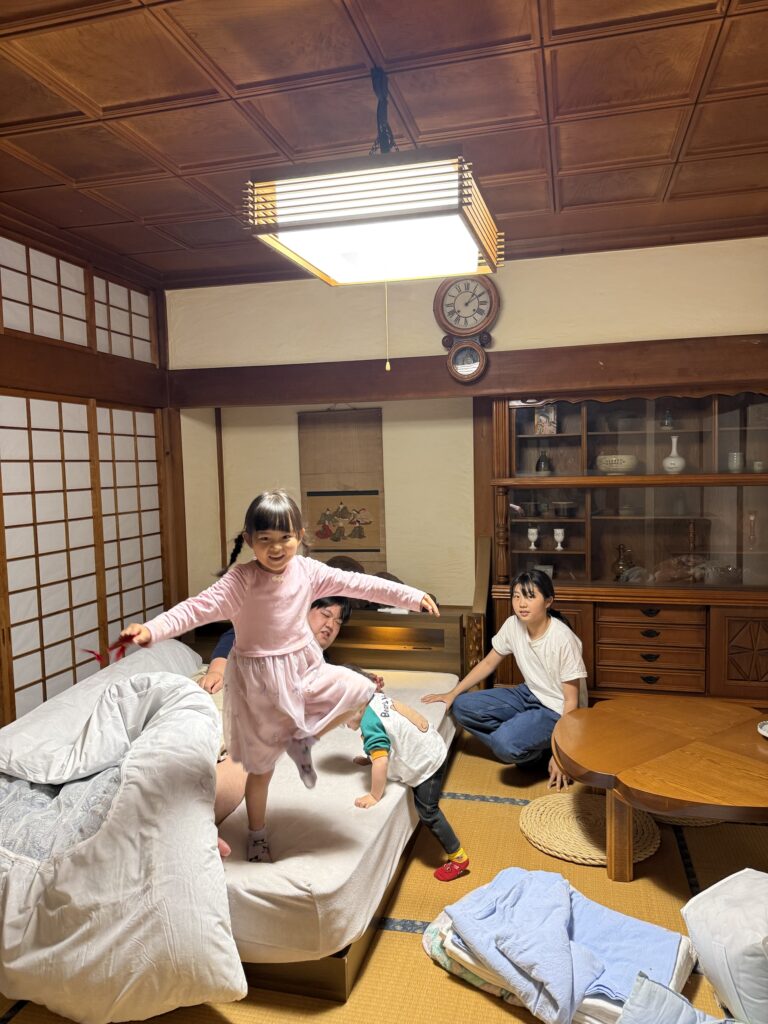 菱花亭の和室で、布団を敷いて子どもたちがはしゃぐ家族旅行の様子