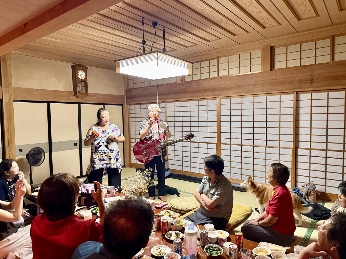 広い和室で、料理と音楽を囲んでにぎやかに過ごす様子